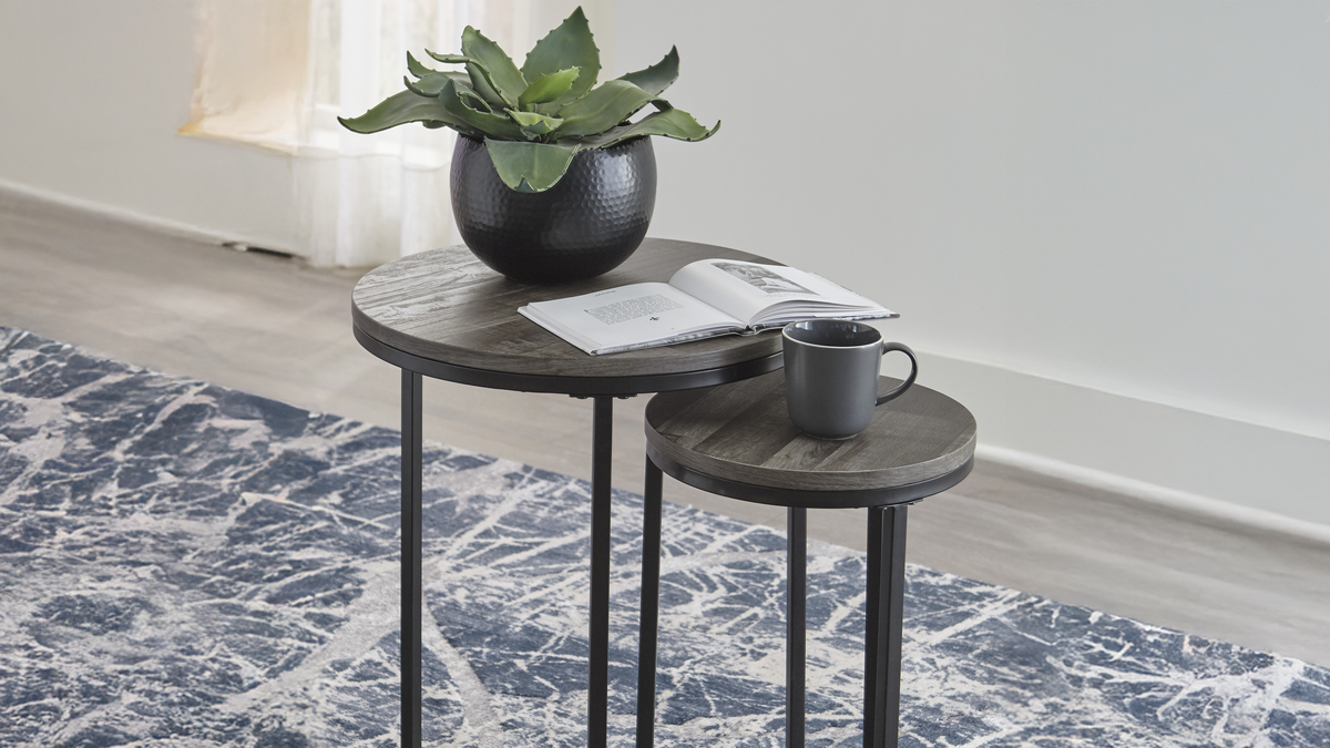 Two black side tables with a plant and books on a patterned rug.