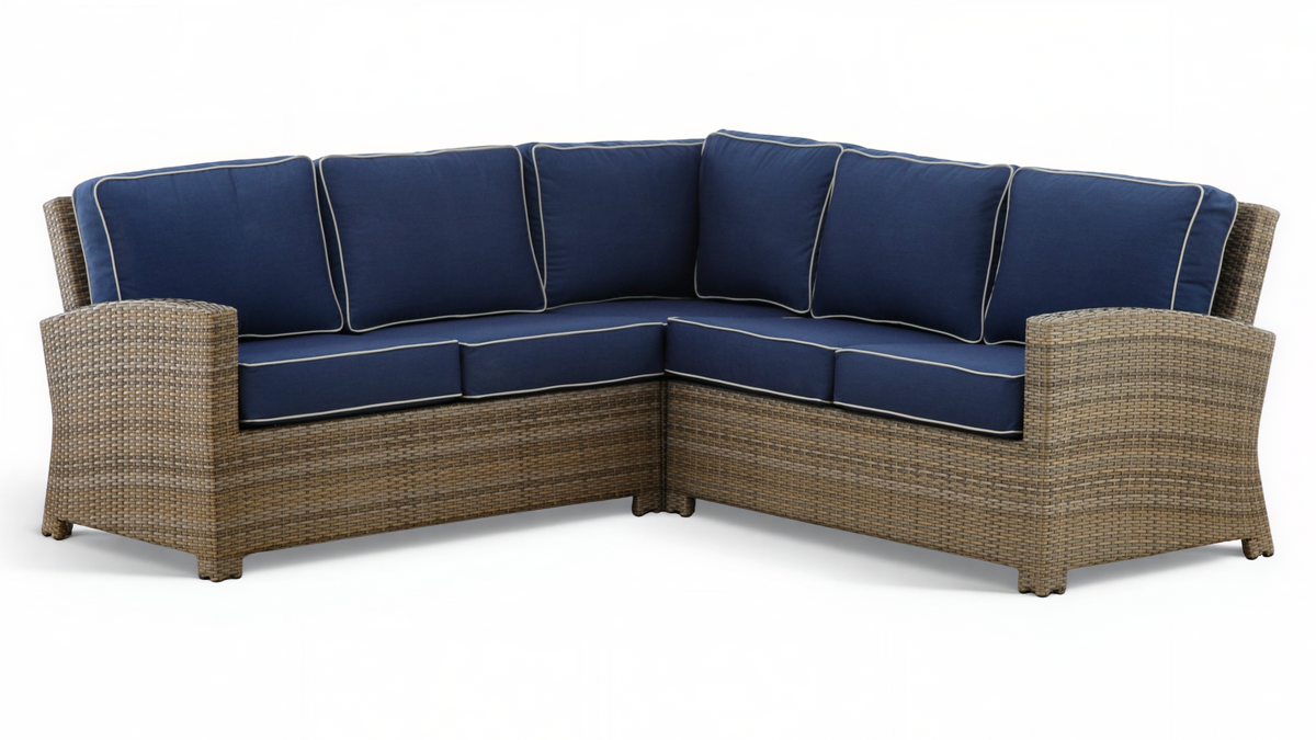 Sectional outdoor sofa with wicker frame and navy cushions on a white background