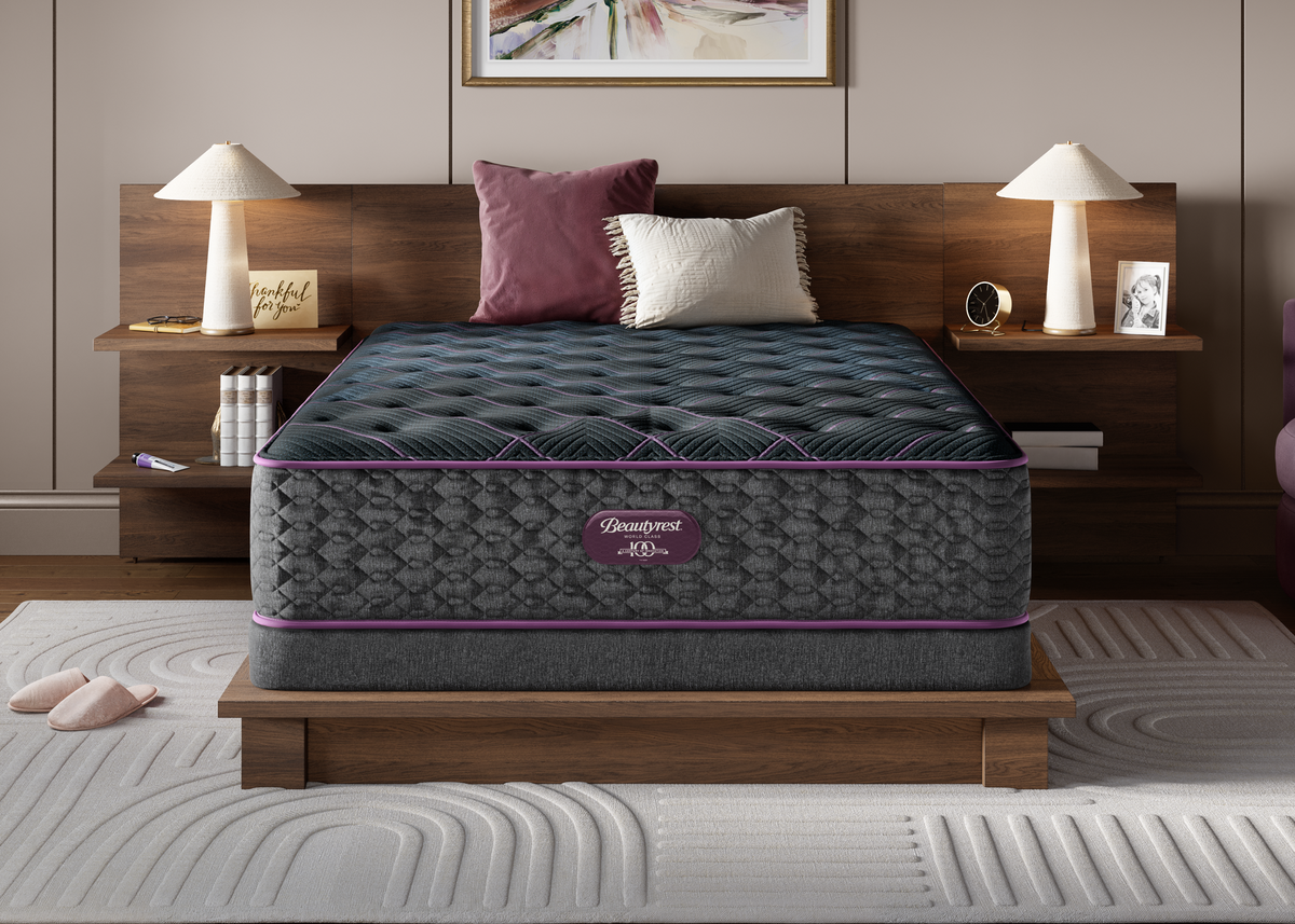 Gray Plush mattress with purple accents on a wooden bed frame in a bedroom setting.