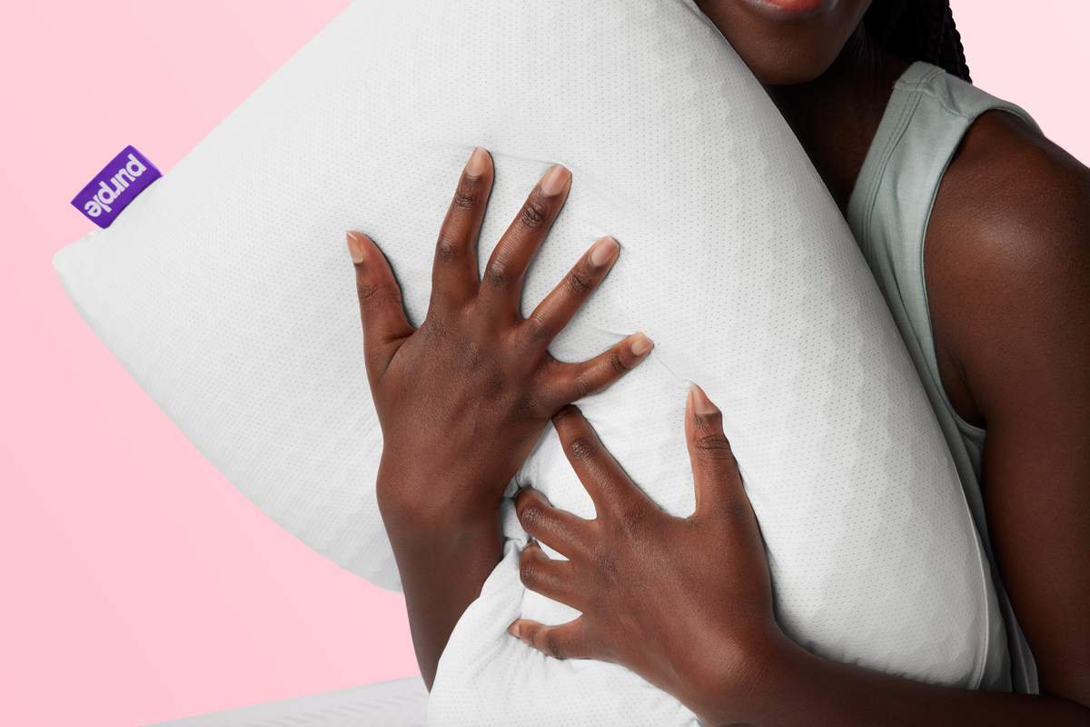 Person holding a white pillow with a pink background